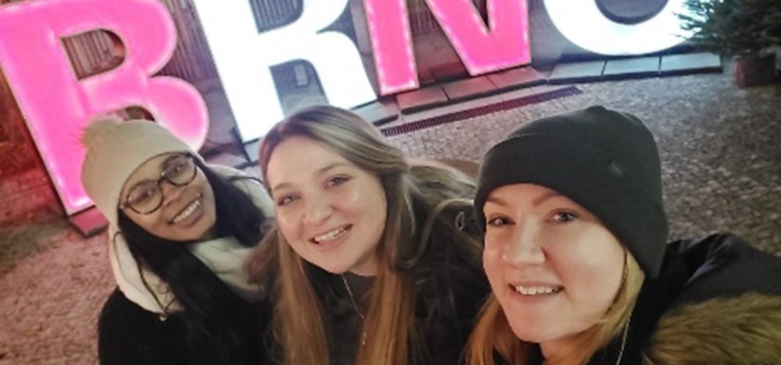 3 students in front of sign